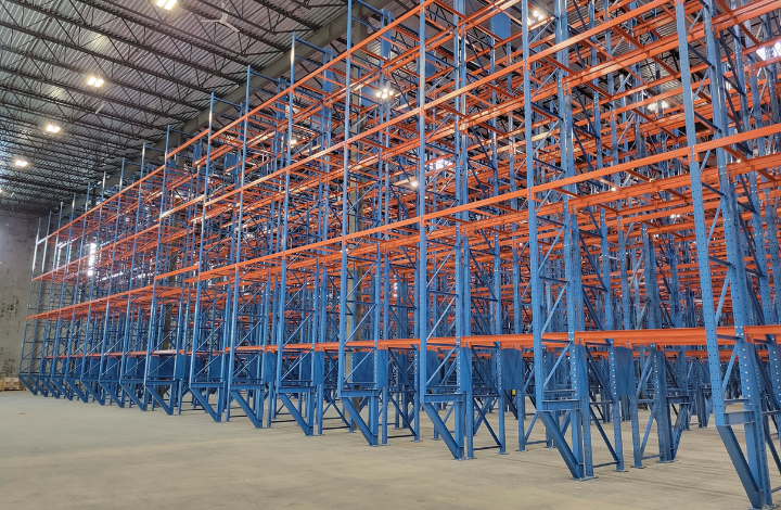 Wide-angle view of a large warehouse filled with blue and orange double deep selective pallet racking structures.