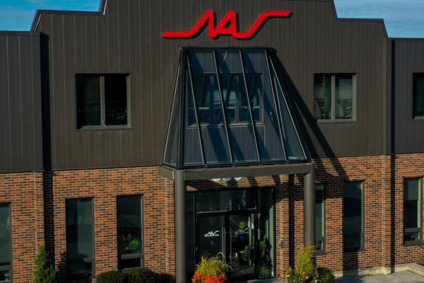 Front view of the North American Steel corporate office building entrance in Whitby, featuring brick exterior, glass entryway, and red NAS signage.