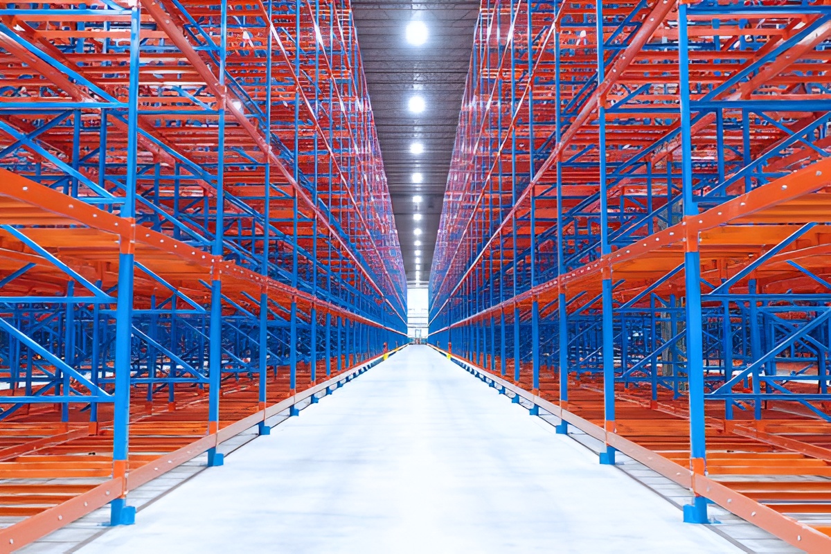 Symmetrical view looking down a central warehouse aisle flanked by orange and blue high-density warehouse racking solutions.