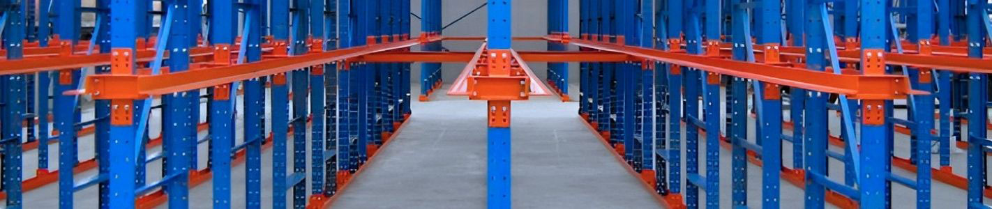 Straight-on perspective view down an empty lane of heavy-duty drive-in pallet racking with blue structural uprights and orange pallet support rails.