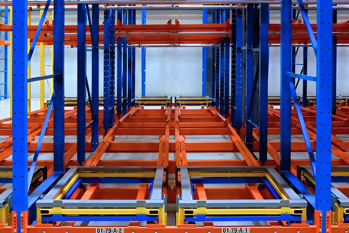 Close-up view of nested cart rails and color-coded pushback nesting trays installed on an industrial rack frame.