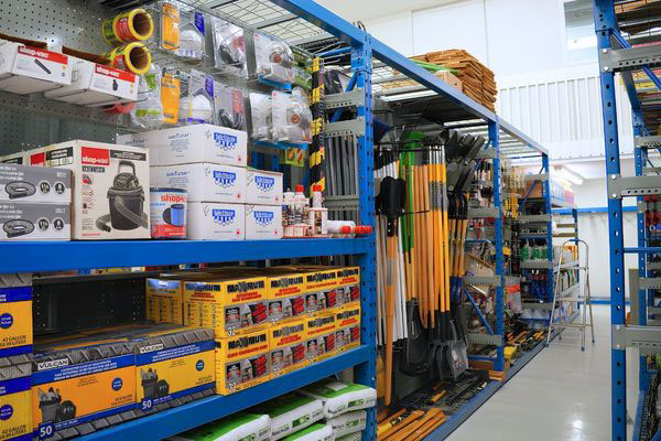 Retail display layout showcasing blue racking integrated with pegboard backings, tool hangers, and shelf storage for hardware merchandise.
